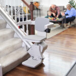Bruno Elan stair lift viewed from the top of the staircase, with family relaxing in the living room below