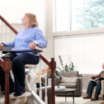 Woman seated on the Bruno Elan stair lift near a sunlit window