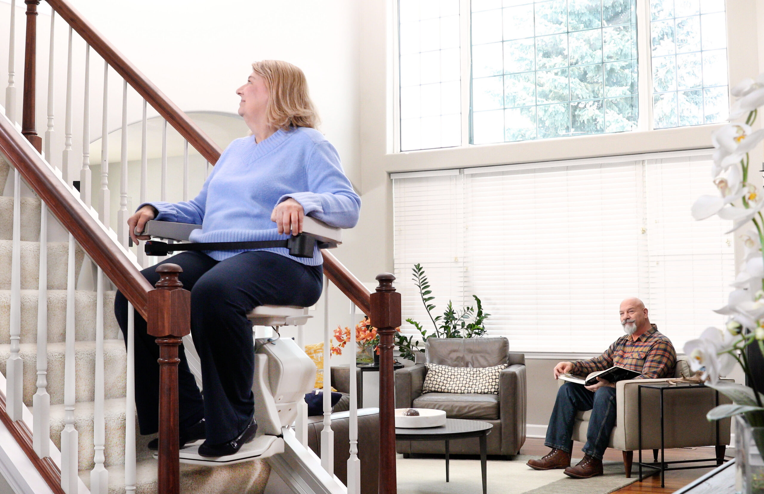 Woman seated on the Bruno Elan stair lift near a sunlit window