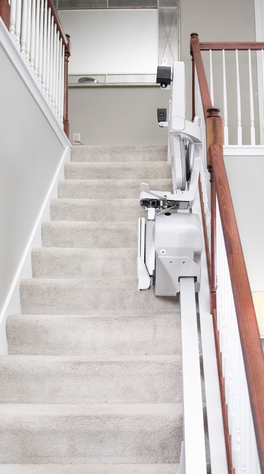 View down a carpeted staircase with the Bruno Elan stair lift folded at the bottom