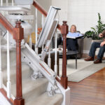 Bruno Elan stair lift installed on an indoor staircase with a family member relaxing in the living room in the background