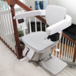 Bruno Elan stair lift parked on a carpeted indoor staircase with wood handrail