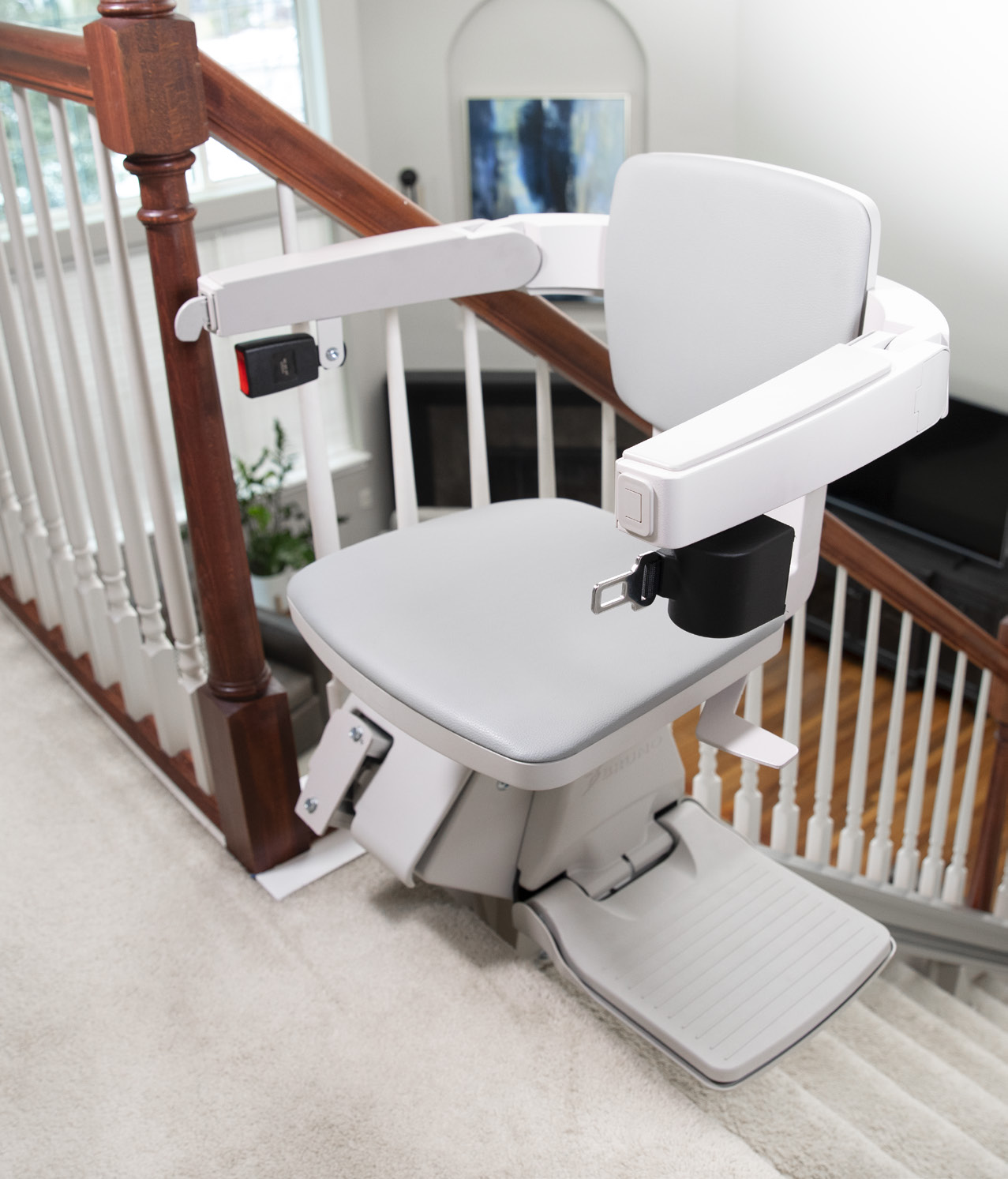 Bruno Elan stair lift parked on a carpeted indoor staircase with wood handrail