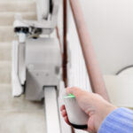 Close-up of a hand pressing the single-button control on the Bruno Elan stair lift armrest