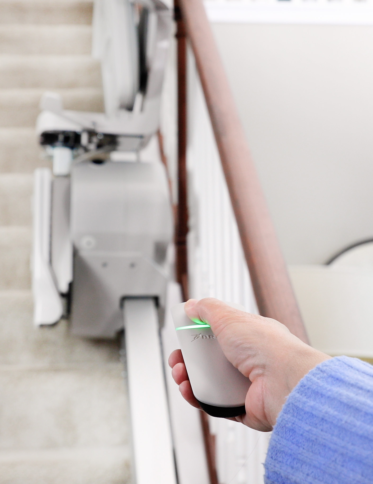 Close-up of a hand pressing the single-button control on the Bruno Elan stair lift armrest