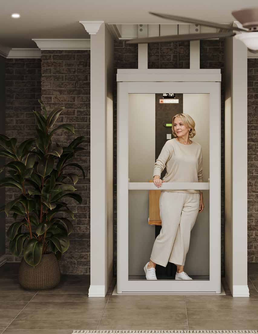Harmar Spire Home Elevator with a full-height glass door and a folded tip-up seat, a woman standing inside the cabin